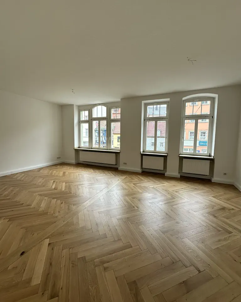 Leere, sorgfältig beräumte Altbauwohnung mit hohen Fenstern, Decke und Fischgrätparkett
