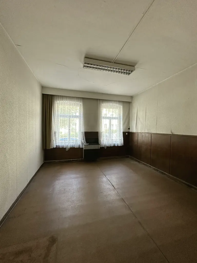 Geräumter leerer Raum mit Fenstern und dunkler Holzverkleidung
